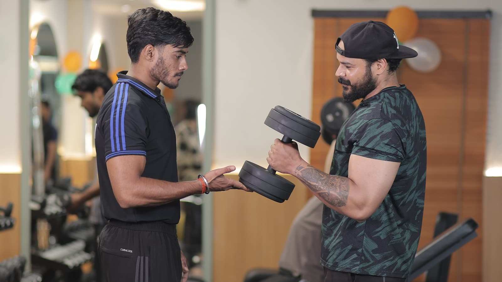 Coach handing a dumbbell to a member in the free weights area
