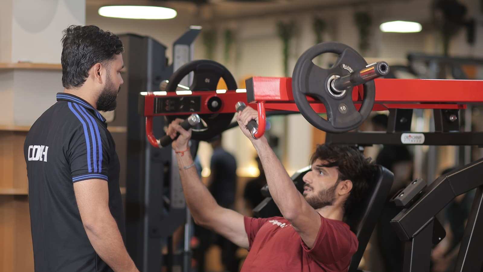Coach spotting a member on the incline chest press