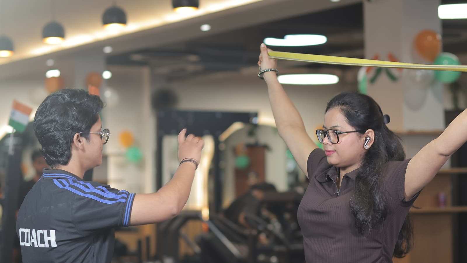 Coach leading a member through an overhead resistance band stretch