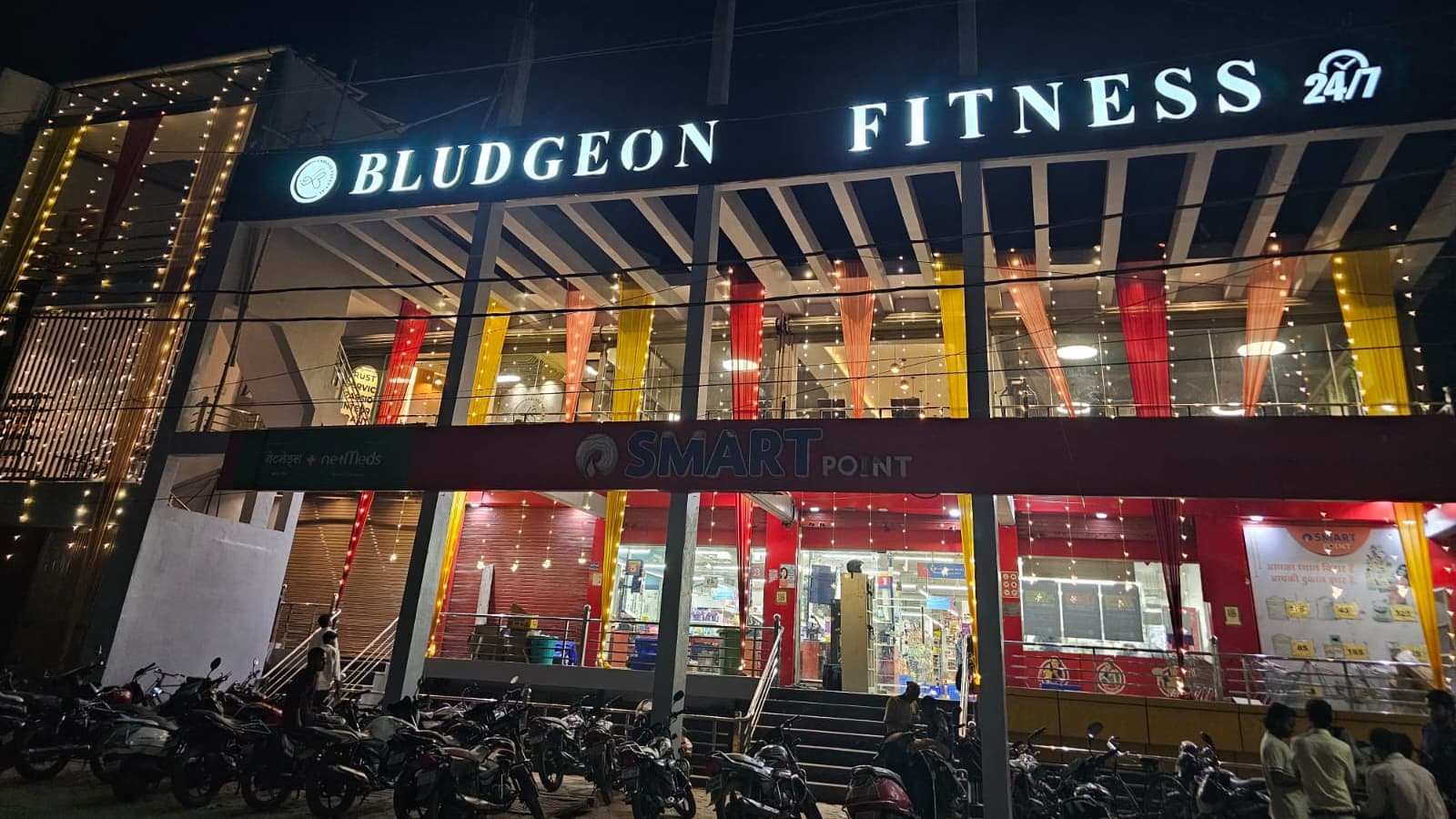 Bludgeon Fitness storefront lit up at night above Reliance Smart Point